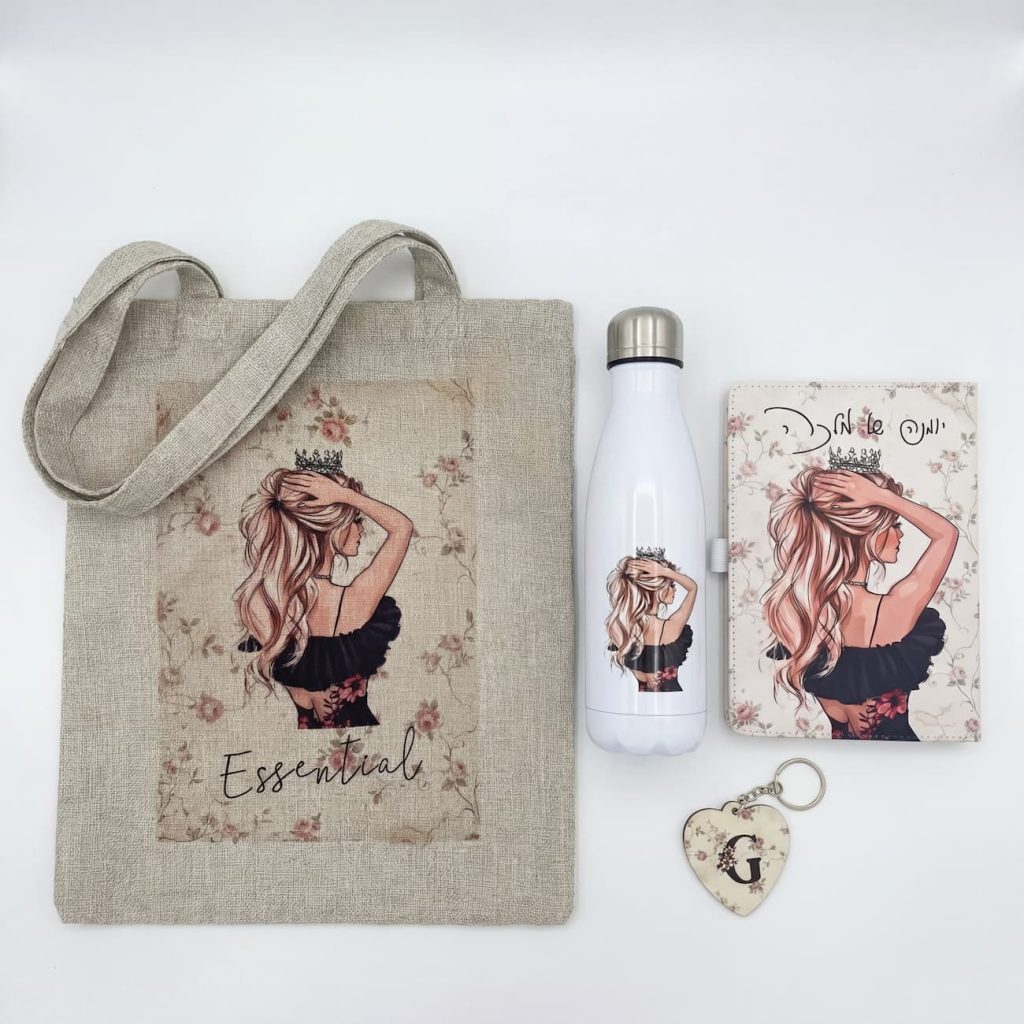 מארז מתנה הכולל תיק בד, בקבוק, מחברת ומחזיק מפתחות עם איור מלכה מצוירת ועליהם הכיתוב "Essentials" ו"יומנה של מלכה" - סט מתנה אישי